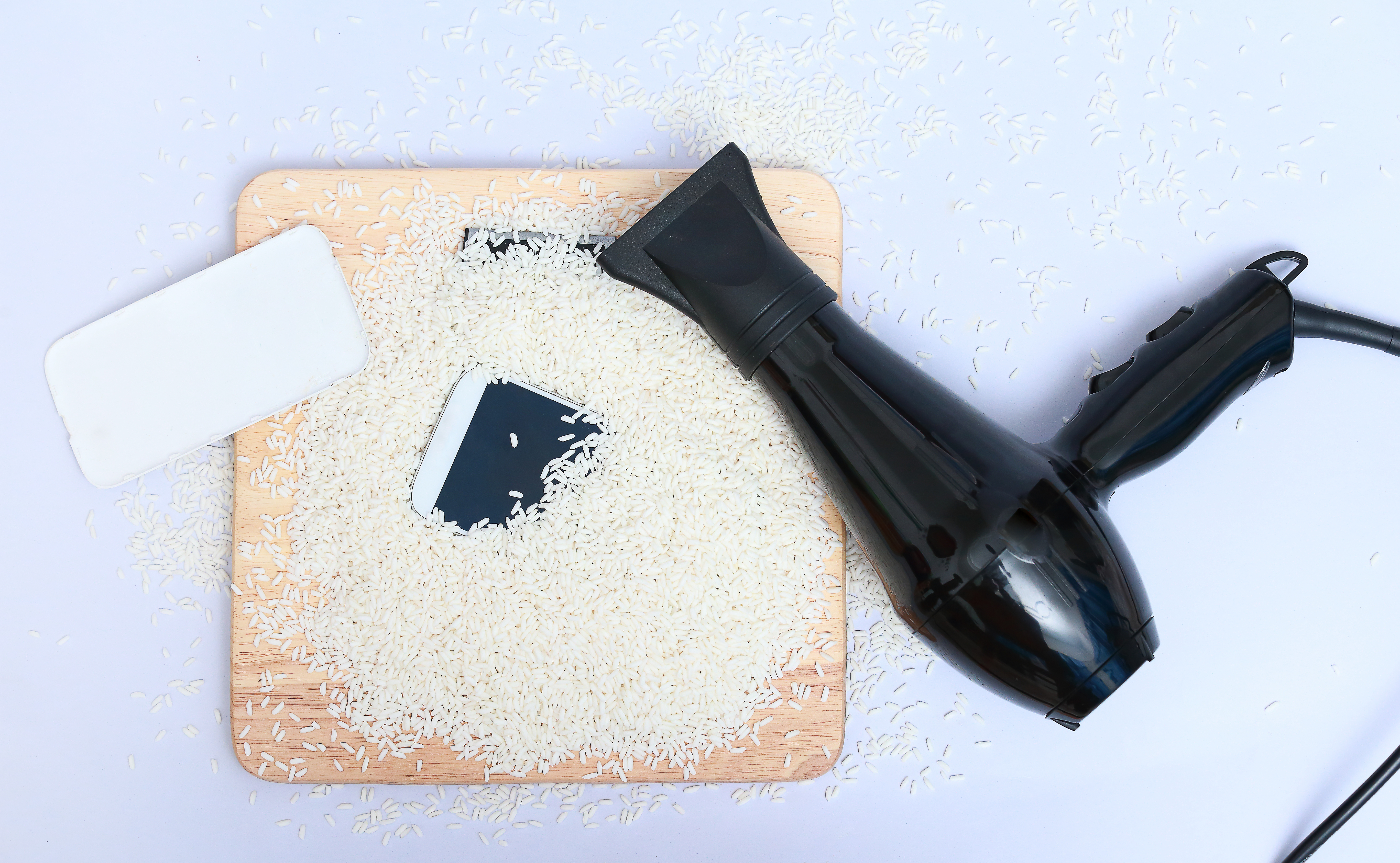 A phone in rice next to a hairdryer