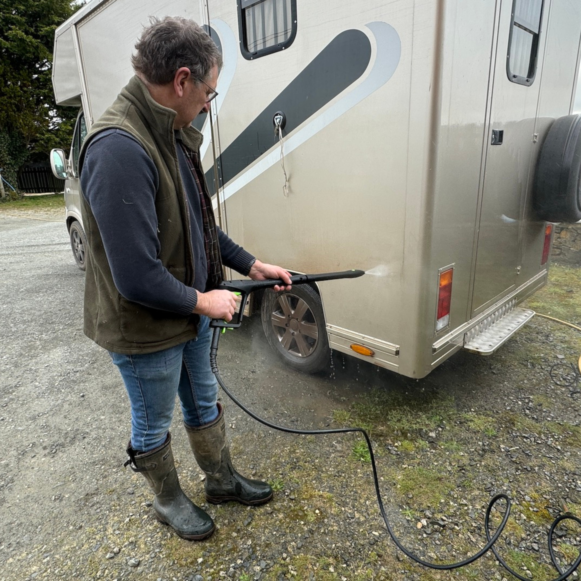 man cleaning a horse box with the greenworks g40 pressure washer