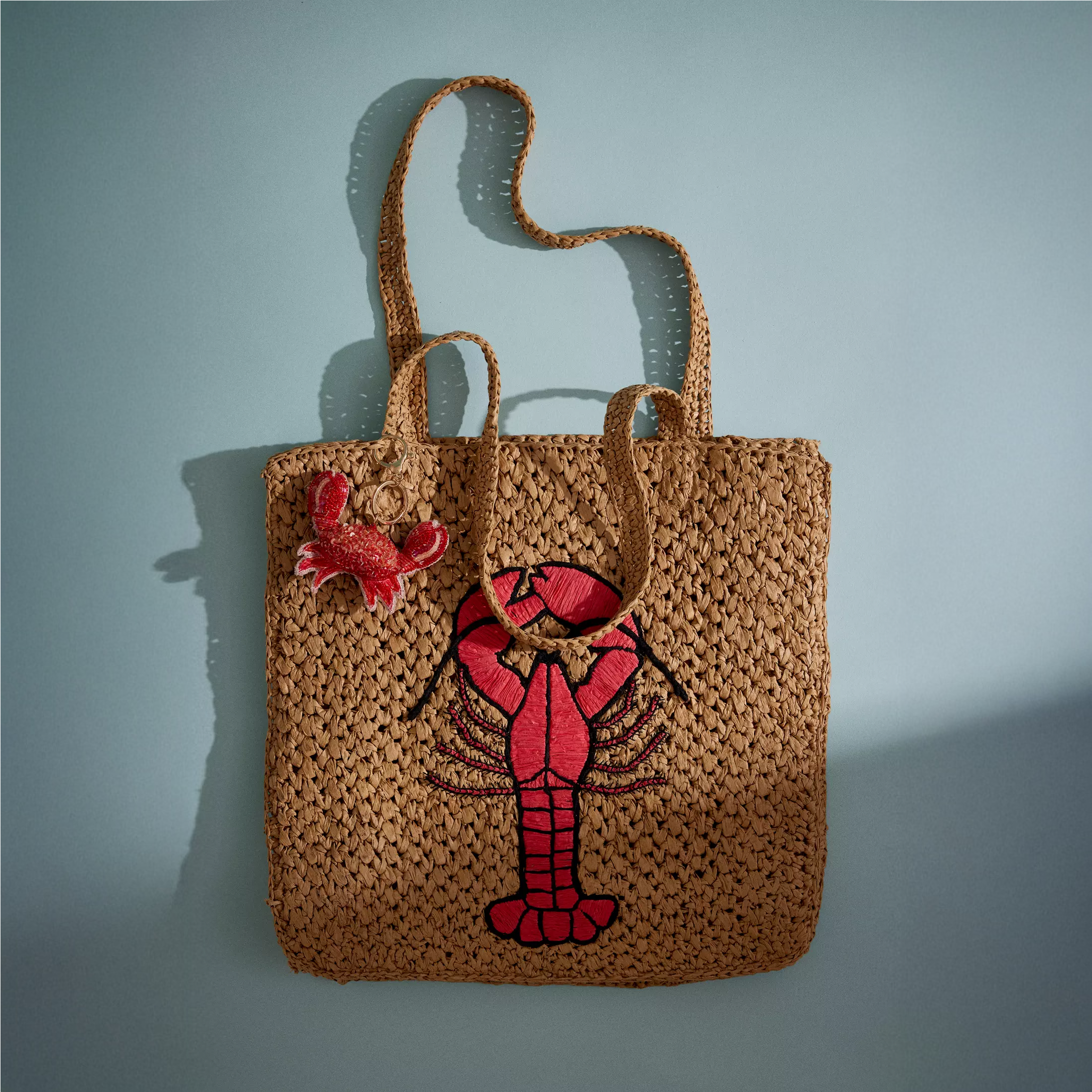 A raffia tote bag with a lobster on the front