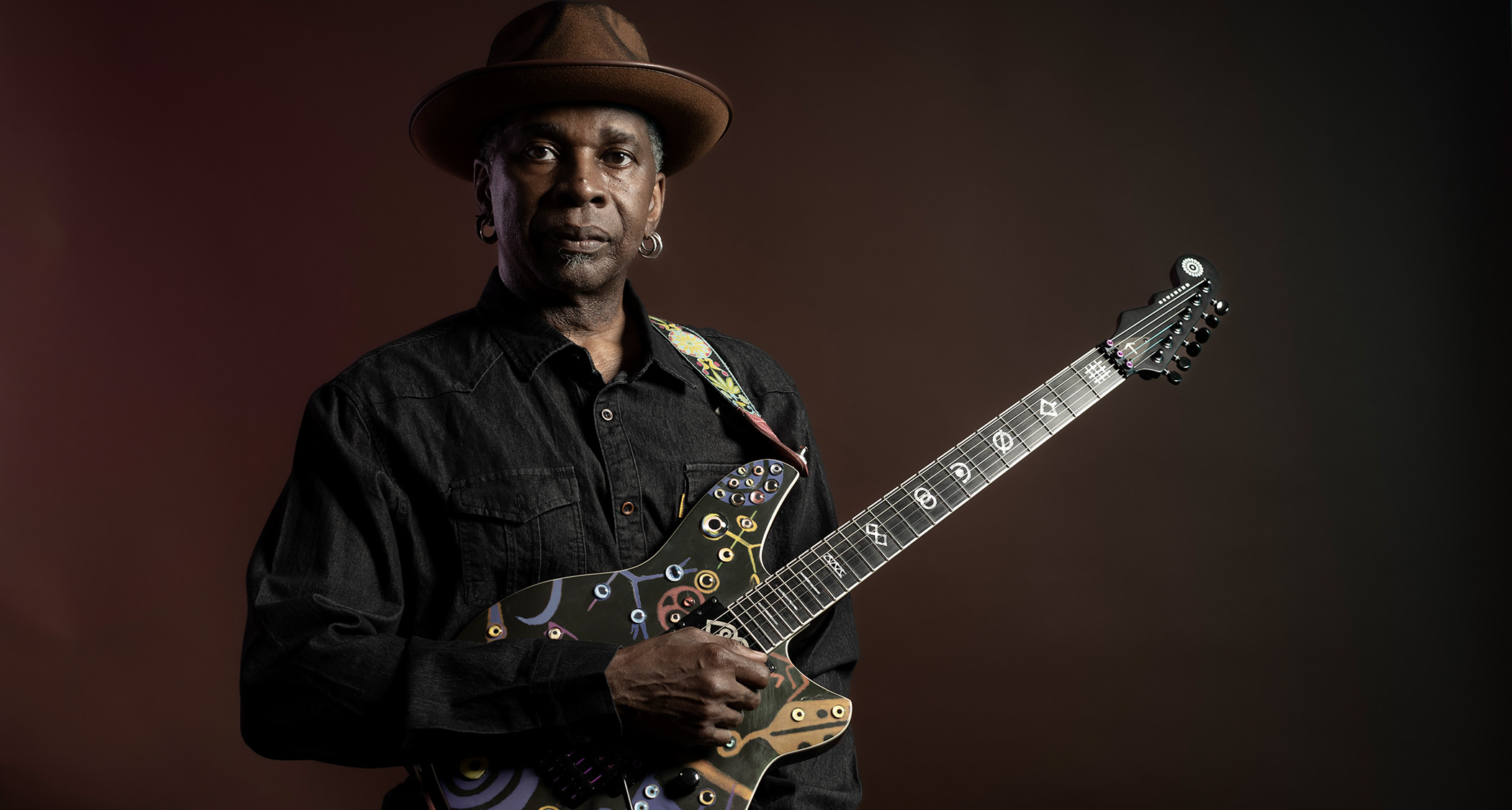 A portrait of Vernon Reid wearing his now trademark hat with his Reverend signature guitar
