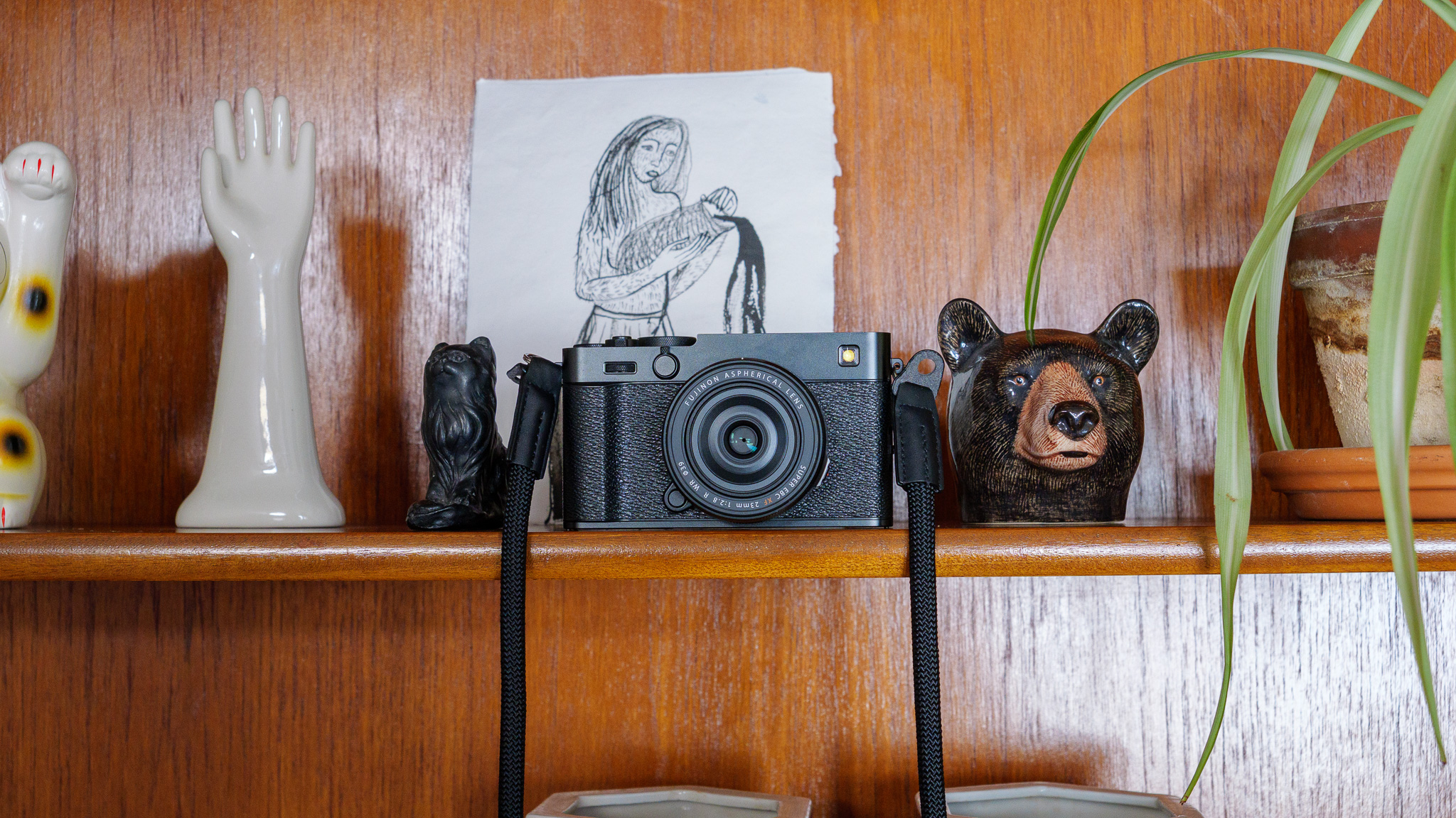 Fujifilm X-E5 camera on wooden shelf surrounded by ornaments