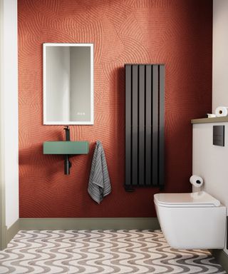 bathroom with orange wall, green sink, white toilet and dark grey vertical radiator