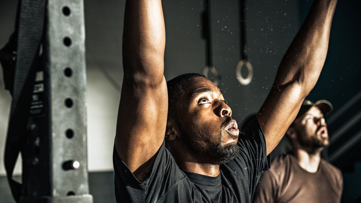 Man in gym with raised arms looking up