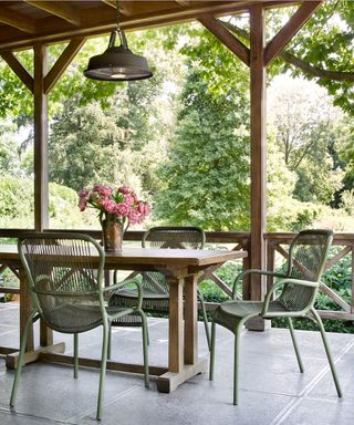 An example of front porch ideas with a wooden table and green chairs