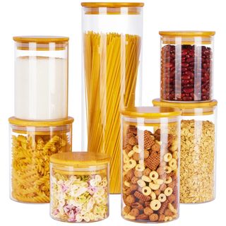 Glass storage jars with bamboo lids in various sizes filled with dried food