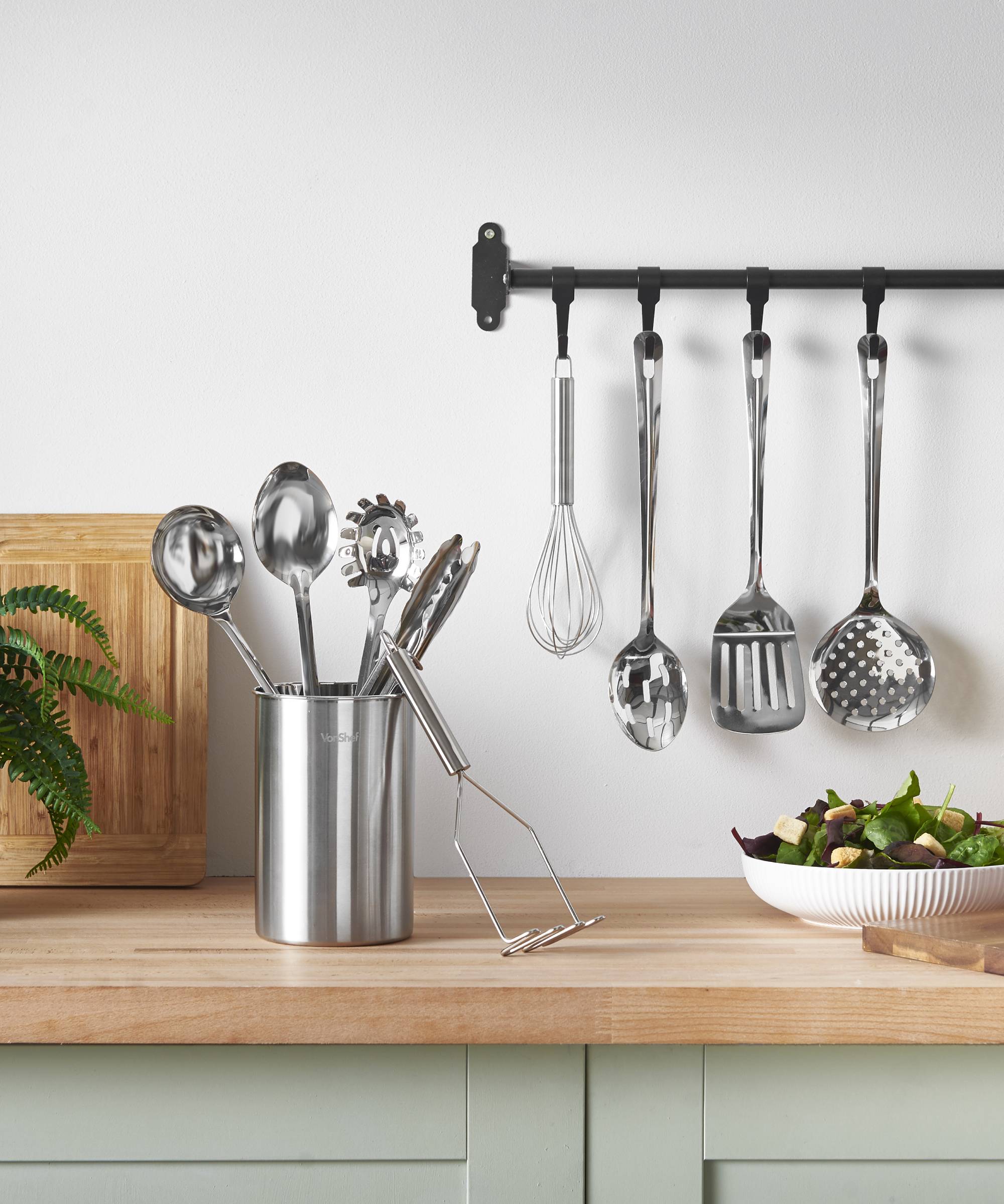 pale green kitchen with wooden worktops and stainless steel utensils on top