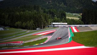 A Ferrari Formula One car sweeps around a corner at the Austrian Grand Prix at the Red Bull Ring in Spielberg