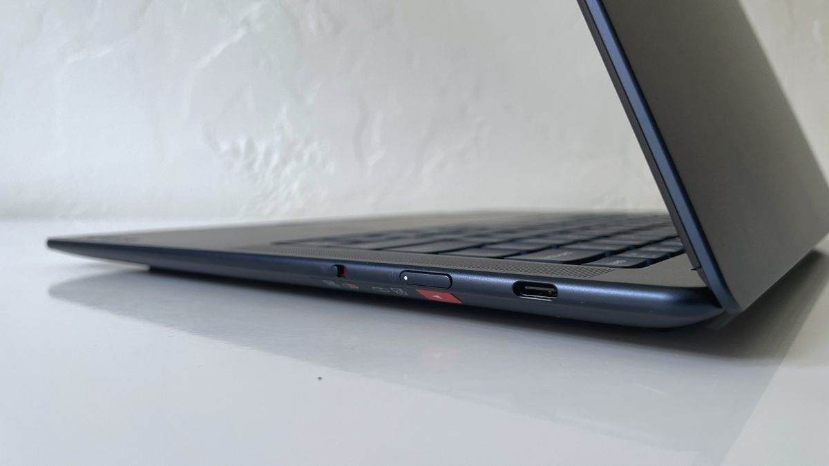 Close up of connectivity ports on the side of a black laptop on top of a white surface.