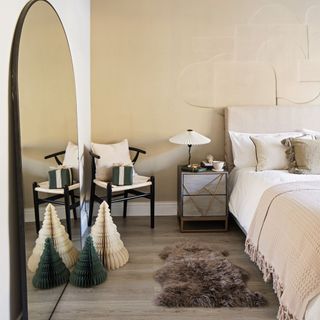 guest bedroom with wall panelling, neutral decor, paper Christmas trees and floor mirror