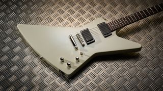 The body of an Epiphone Explorer 80s EMG electric guitar lying on some sheet metal