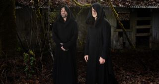 Hooded and robed, Greg Anderson (left) and Stephen O'Malley of Sunn O))) pose in front of a derelict barn.