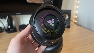 Reviewer's hand holding earcup of Razer Kraken V4 Pro with RGB on