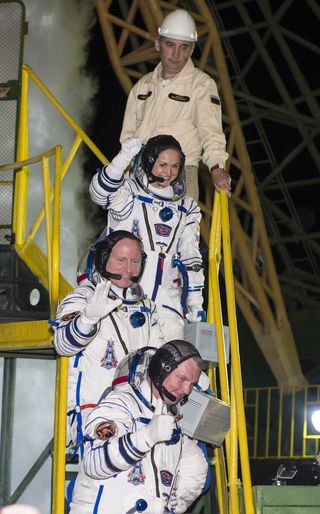 Expedition 41 Soyuz Commander Alexander Samokutyaev of the Russian Federal Space Agency (Roscosmos), bottom, Flight Engineer Barry Wilmore of NASA, middle, and Elena Serova of Roscosmos, top, wave farewell prior to boarding the Soyuz TMA-14M spacecraft fo