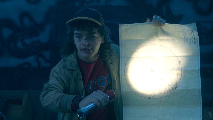 Dustin shining a flashlight at a map he's holding in Stranger Things Season 5