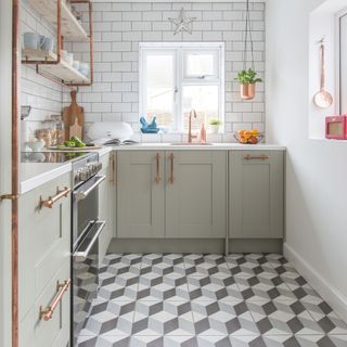 White kitchen with light green cabinets, geometric tiled floor, and white worktops