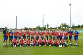 Players of England pose for a group photo holding signs saying 'Show racism the red card', following a training session at St George's Park on June 23, 2023 in Burton upon Trent, England.
