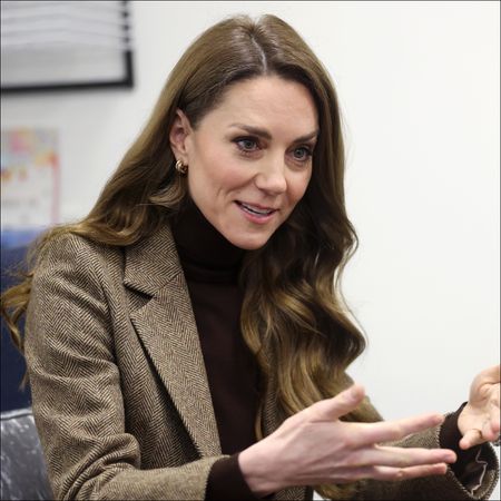 Kate Middleton wearing a tweed jacket and with long brown brunette hair with waves