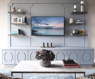 A white TV unit with a hung flatscreen TV surrounded by shelves