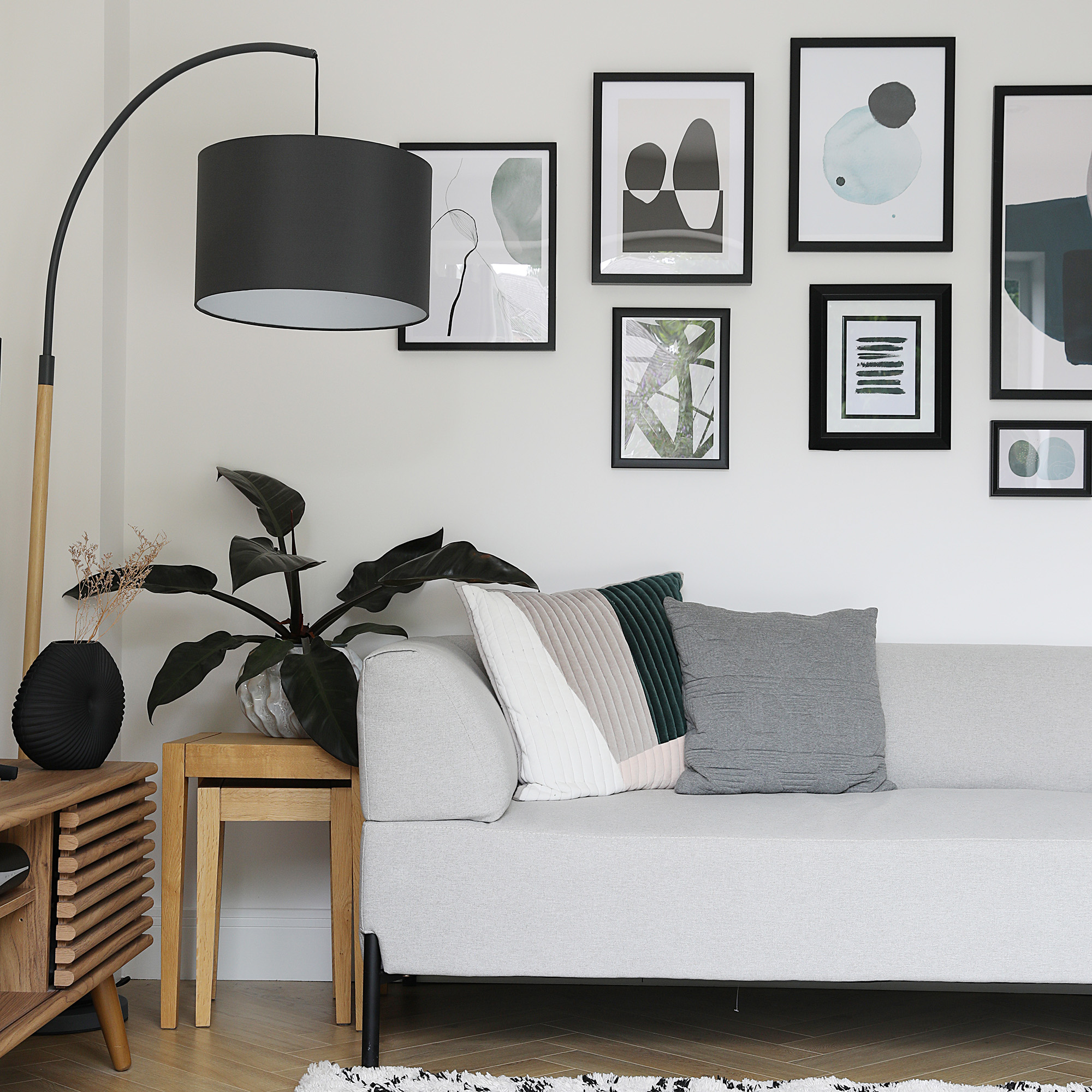 living room with grey sofa with gallery wall with minimalist abstract print and black frames and lamp hanging black lampshade