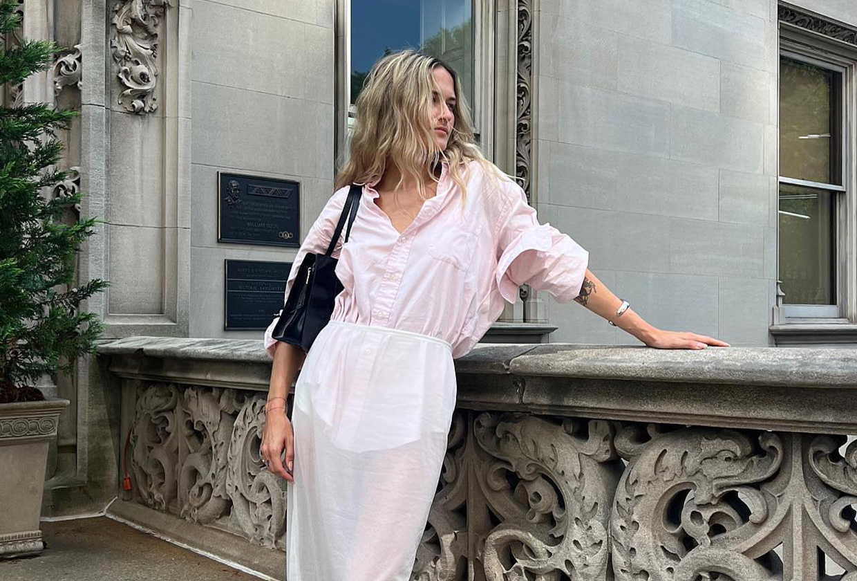 Eliza Huber wearing a pink button-down shirt tucked into a sheer white skirt with a black bag.