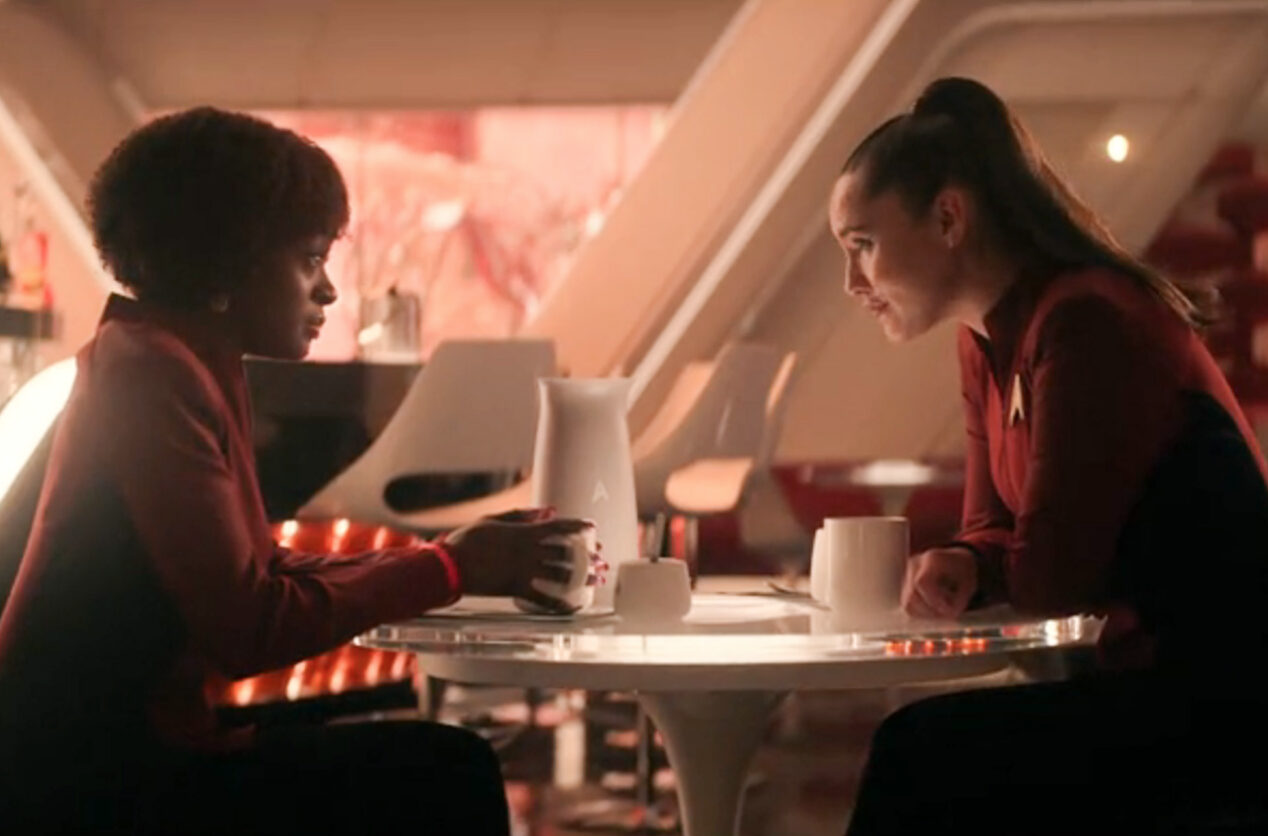two sci-fi characters at a table on a starship