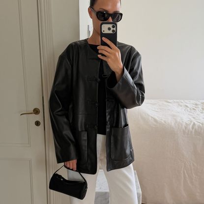 Woman in a black leather jacket and white jeans