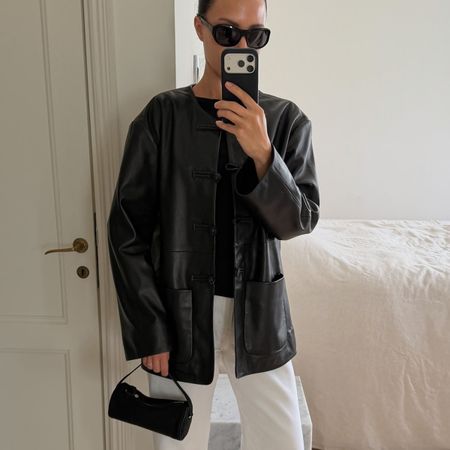 Woman in a black leather jacket and white jeans
