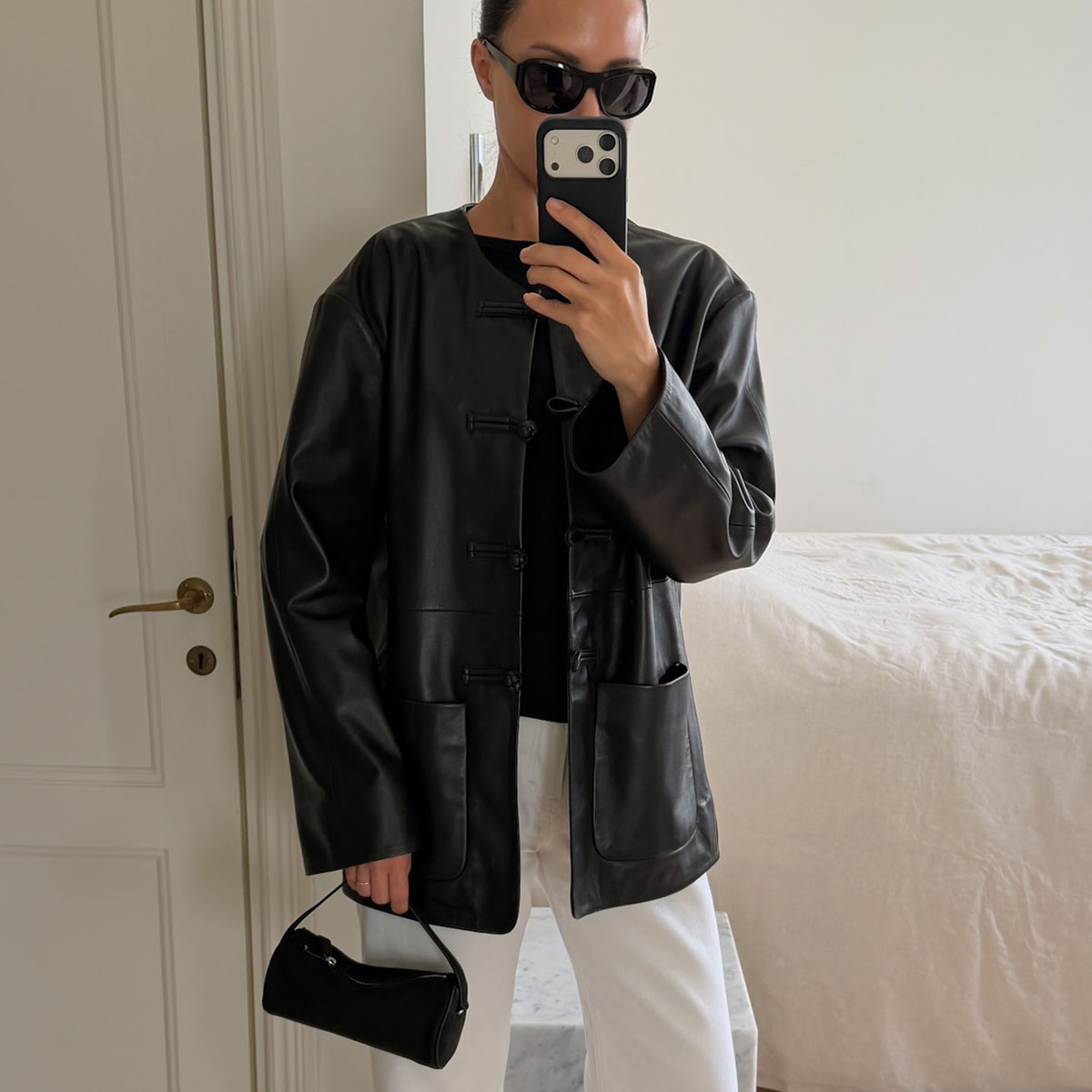Woman in a black leather jacket and white jeans