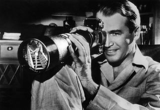 james stewart looks through a camera lens out the window in the movie Rear Window (1954)