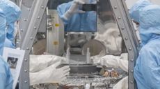 OSIRIS-REx curation team members at NASA&rsquo;s Johnson Space Center begin the process of removing and flipping the TAGSAM (Touch-and-Go Sample Mechanism) from the avionics deck of the mission's science canister.