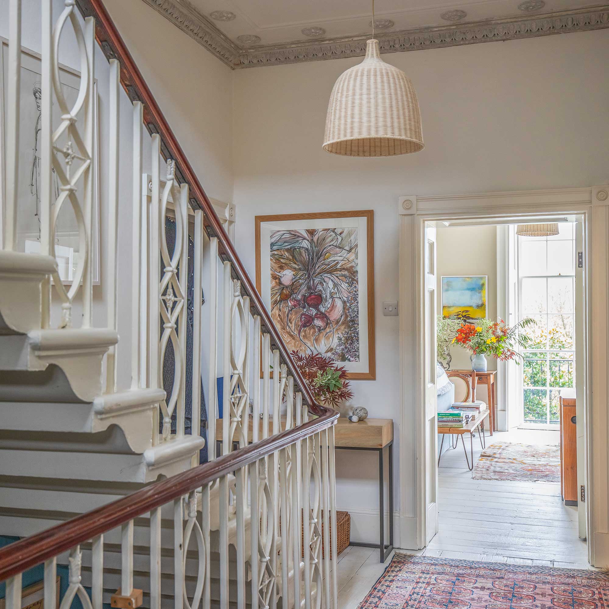 landing in a georgian village with decorative balustrades, ornate cornicing and view through to room with large sash windows
