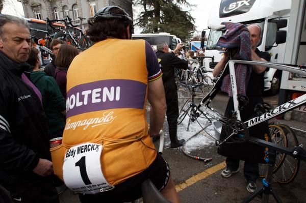 An Eddy Merckx lookalike arrives at the finish as the team mechanics clean the bikes