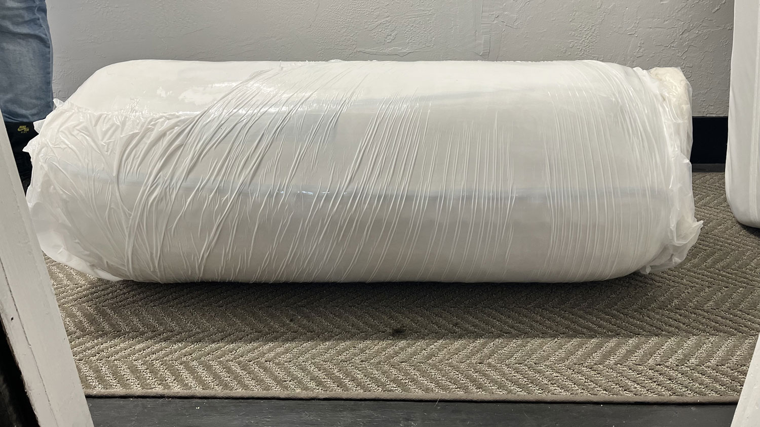 The Avocado Green mattress rolled up in plastic