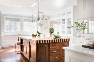 A white modern kitchen with a wooden island with a checkerboard style countertop