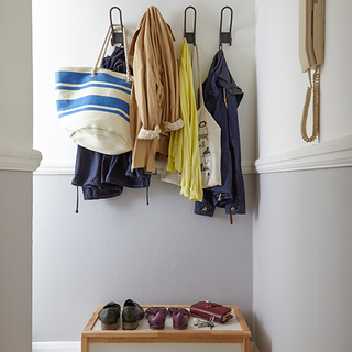 hallway with hanging cloths on wall and shoes purse on table