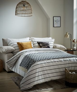 A small white bedroom with nautical striped duvet and sofabed