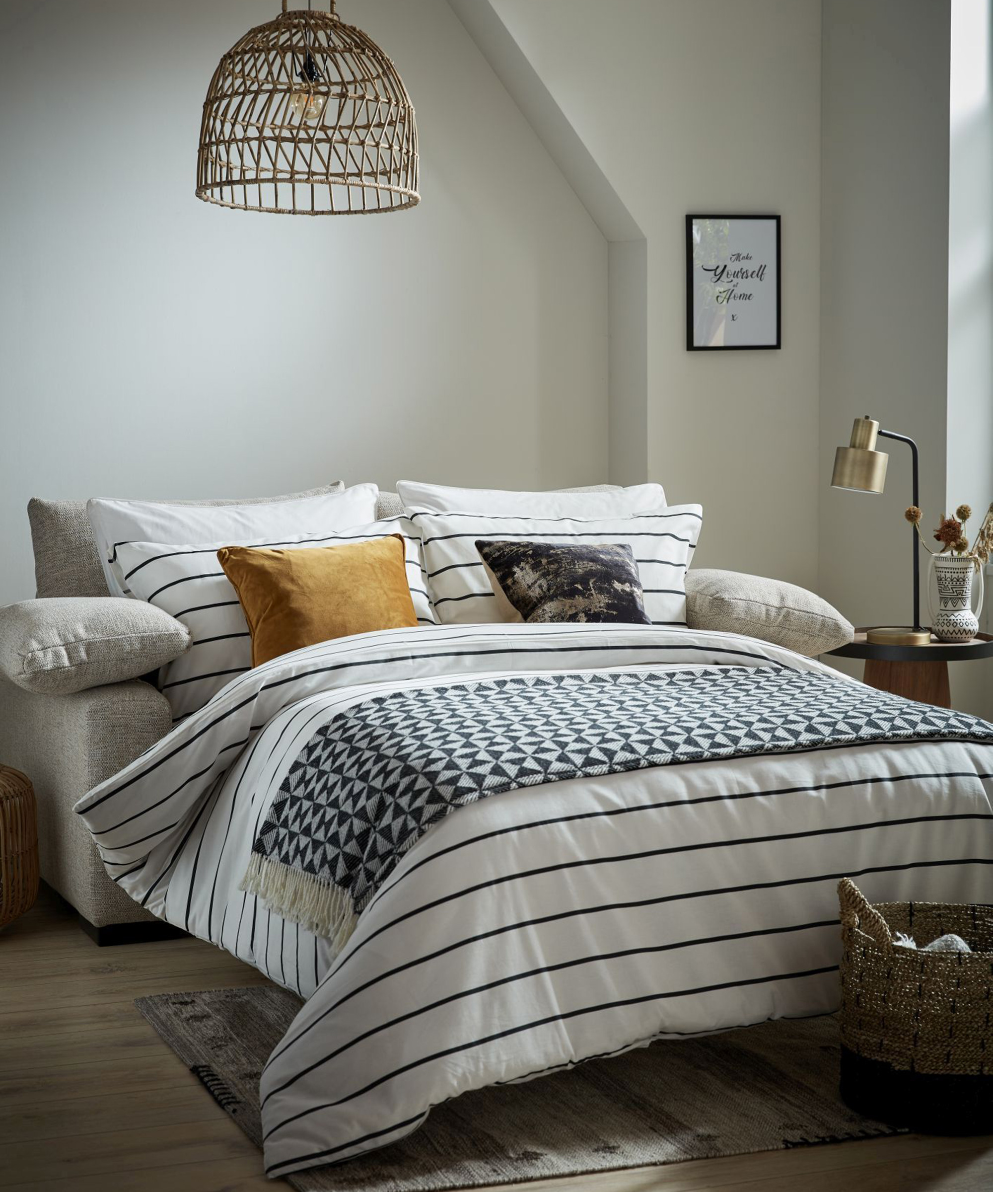 A small white bedroom with nautical striped duvet and sofabed