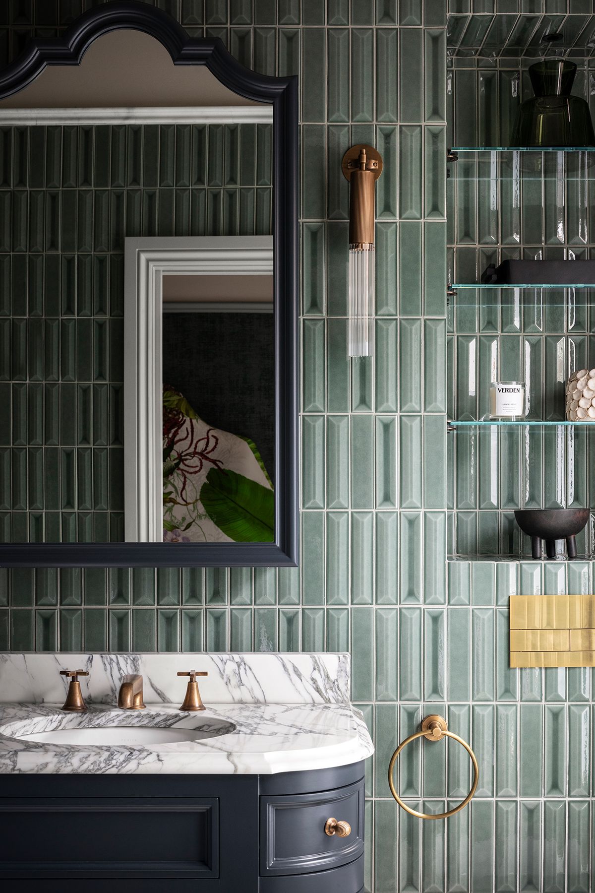 Tall rectangular tiles in green in a bathroom. There is also a large mirror and open shelving in the space.