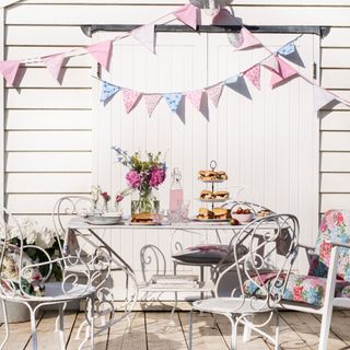 A garden furniture set with a flower vase and bunting above it
