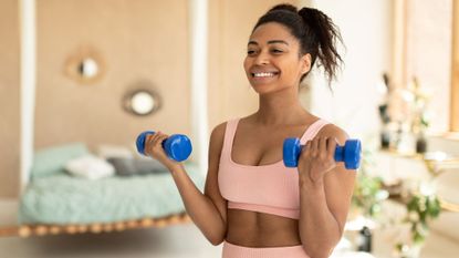 A woman holding dumbbells doing a home workout