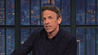 Seth Meyers talks at his desk during a Late Night episode.