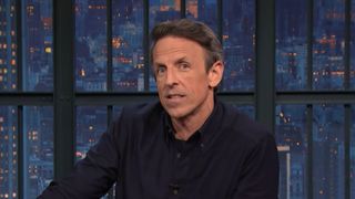 Seth Meyers talks at his desk during a Late Night episode.