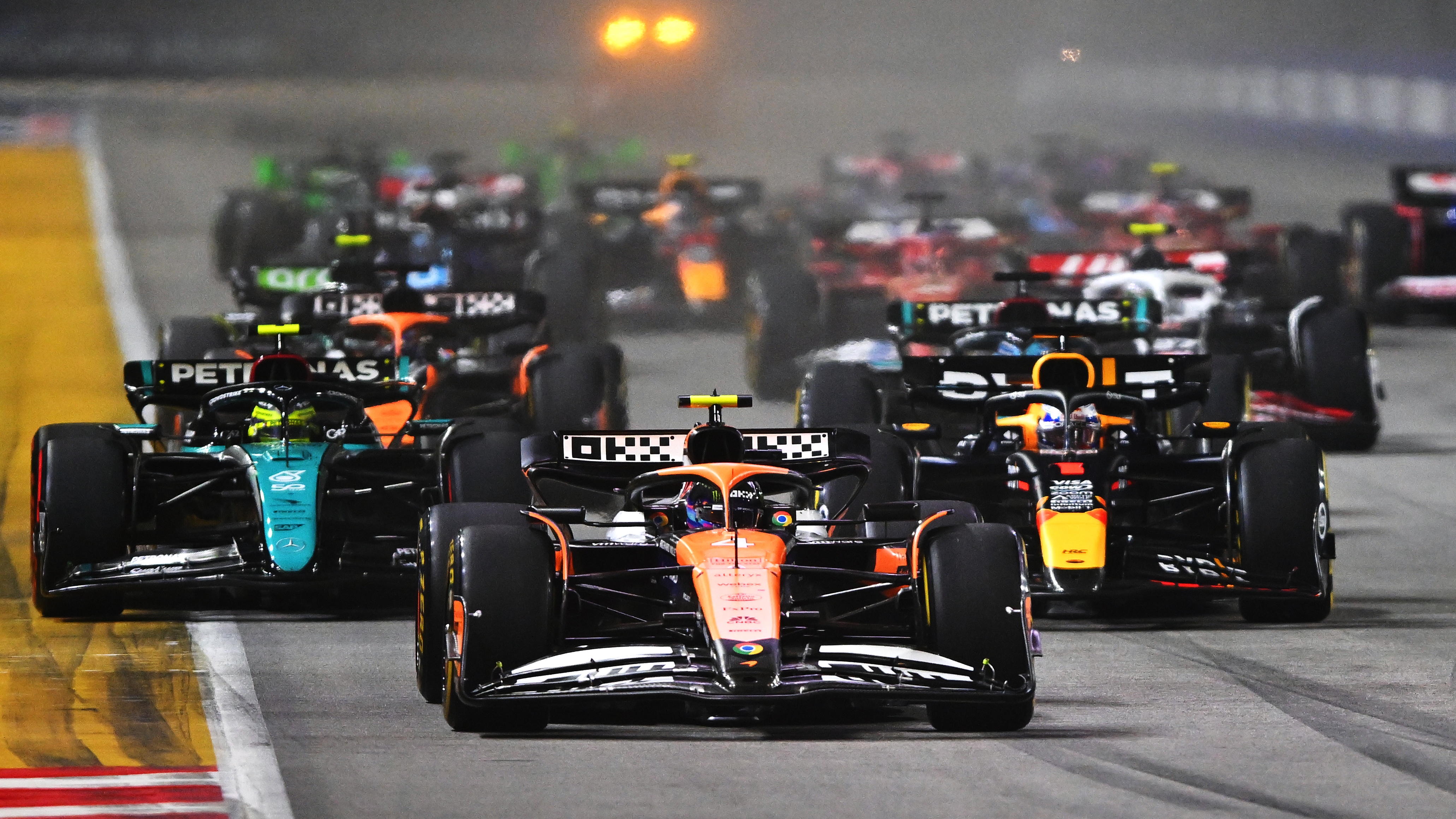  Lando Norris of Great Britain driving the (4) McLaren MCL38 Mercedes leads Max Verstappen of the Netherlands driving the (1) Oracle Red Bull Racing RB20 and the rest of the field into turn one at the start during the F1 Grand Prix of Singapore at Marina Bay Street Circuit on September 22, 2024 in Singapore, Singapore. 