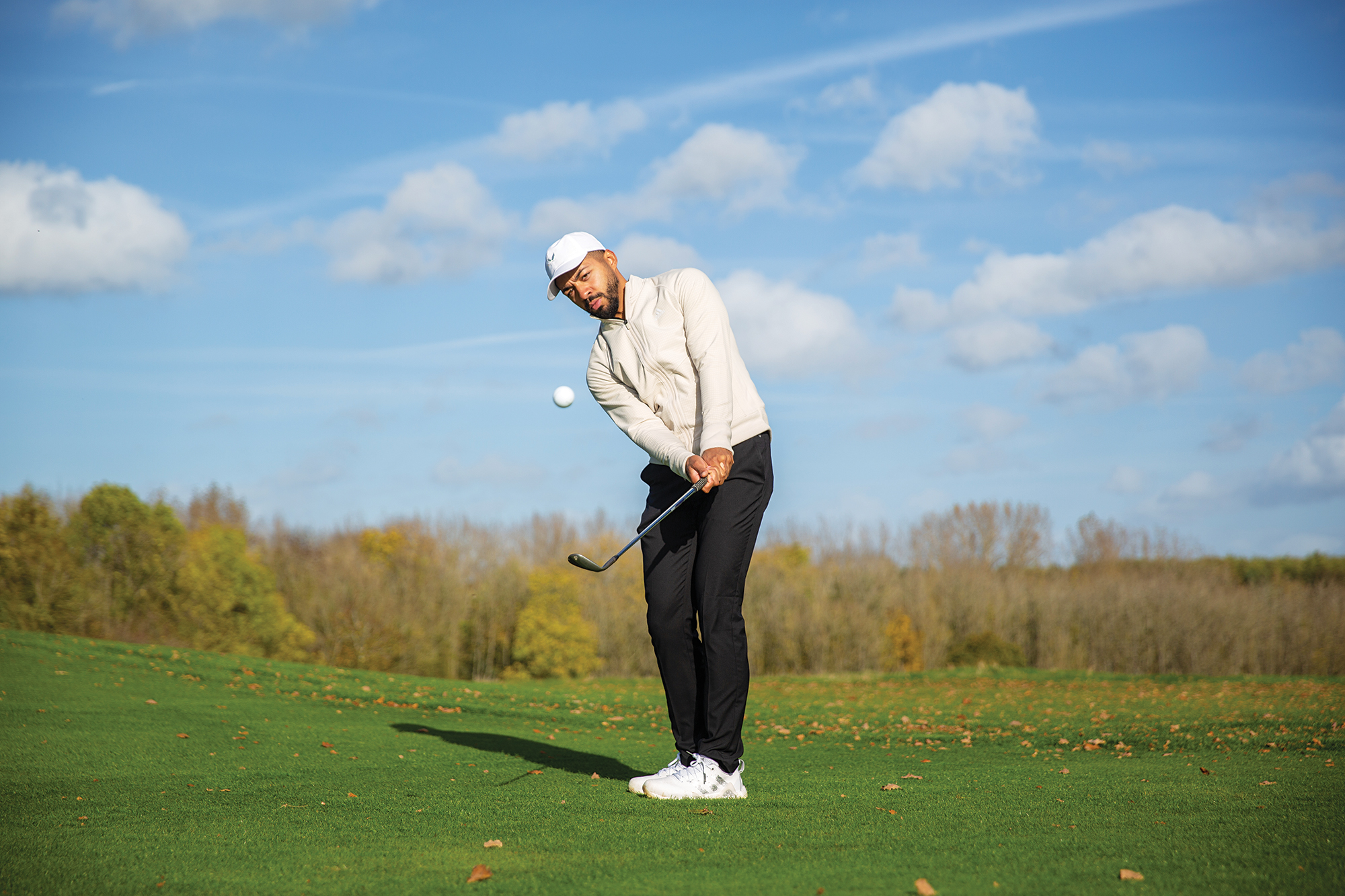 Trey Niven putting spin on his chip shot with a wedge, with the ball coming off the clubface and travelling through the air