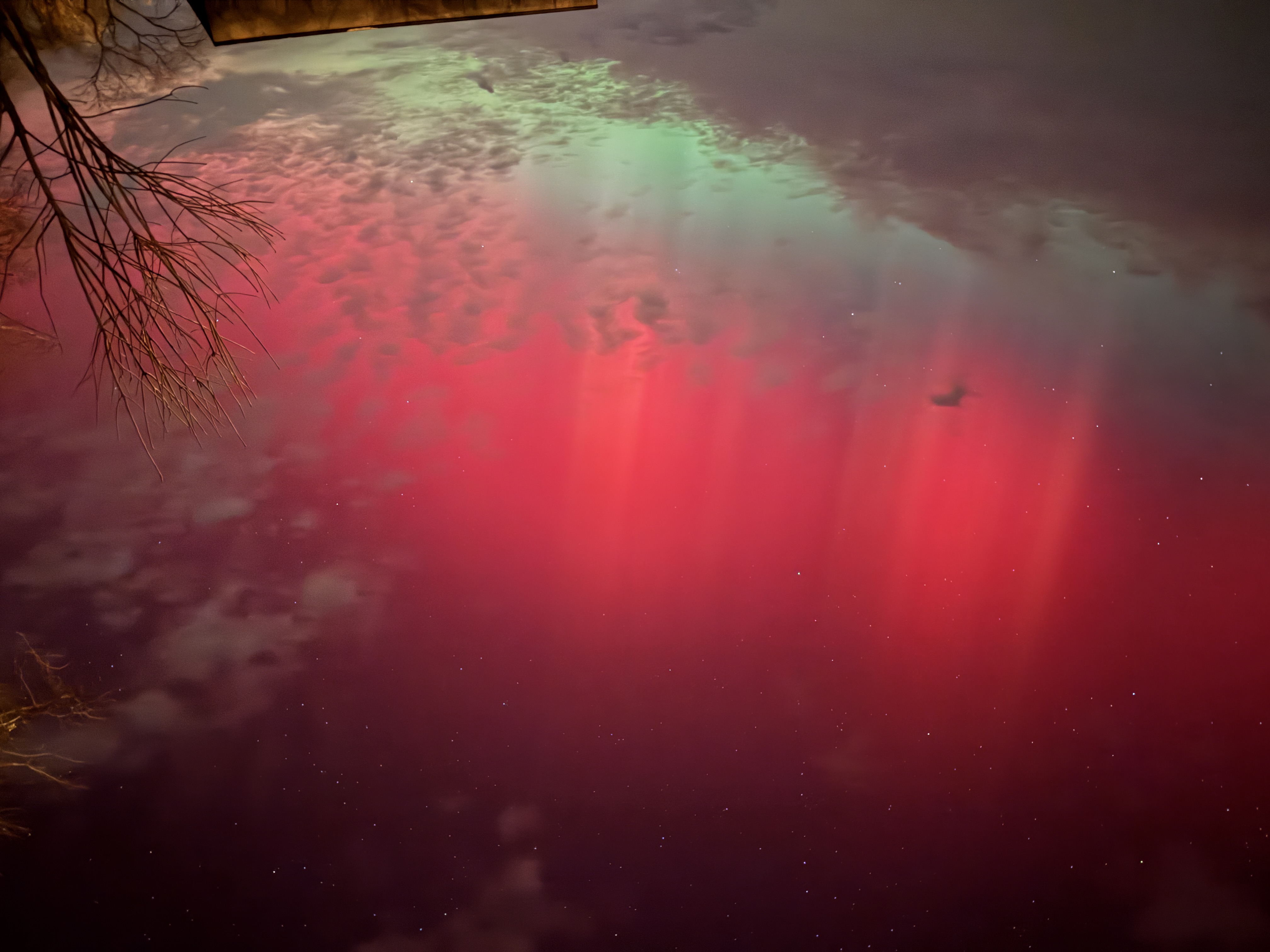 北極光在天空中呈現為紅色和綠色光幕。