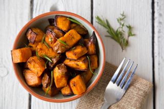 Sweet potato in bowl, next to a fork, one of the foods that can help people to lose weight