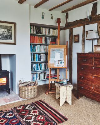 room beams and stove lit with artists easel and chest of drawers and colorful rug