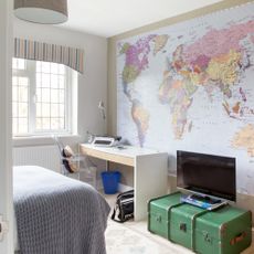 A teenager's bedroom with a large world map poster on the wall