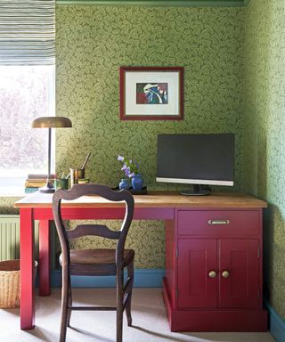 Green home office with floral wallpaper and pink desk
