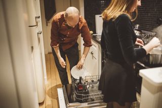 couple loading dishwasher in the kitchen at night